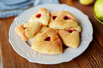 Naklejka na ściany i meble Close-up view of freshly baked triangular raspberry buns lying on white elegant plate