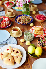 Tasty homemade buns, freshly baked pies, ripe fruits and berries from garden and cups of scented tea placed on large wooden table