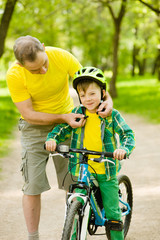 Naklejka premium Grandfather wears a bicycle helmet to his grandson