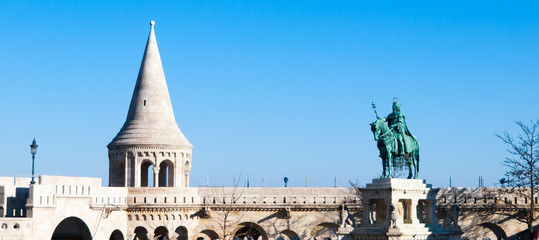 Naklejka premium Mounted statue of Saint Stephen I, aka Szent Istvan kiraly - the first king of Hungary at typical white rounded tower of Fisherman's Bastion in Buda Castle in Budapest, Hungary, Europe. Sunny day shot