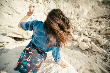 Young woman posing and dancing near the beautiful mountains dressed colorful clothes