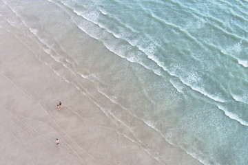 texture of the sea’s wave approach to the sand at lowest tide in aerial view