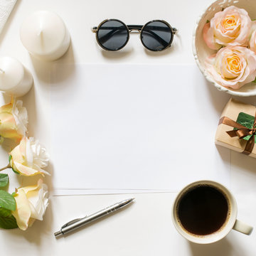 Square crop. Empty sheet with copy space on the white desk with coffee cup, sunglasses, roses and vintage white tray. Top view, flat lay, copyspace.
