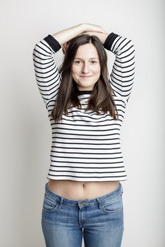 girl in blue jeans and a striped sweater and lifted her arms bared belly with a beautiful waist and umbilicus