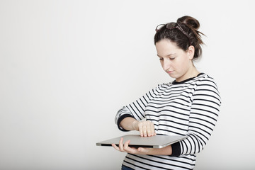 beautiful young girl trying to open a closed notebook lying in hand, dressed in a striped sweater, black hair on the head and glasses