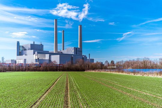 Heizkraftwerk neben einer Solaranlage und einem gr&uuml;nen Feld