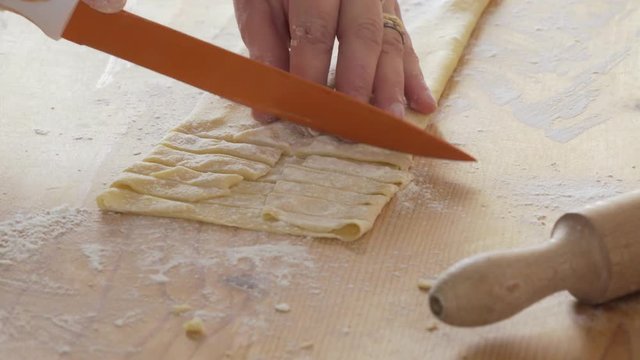 woman hand cutting fresh dough making fettuccine