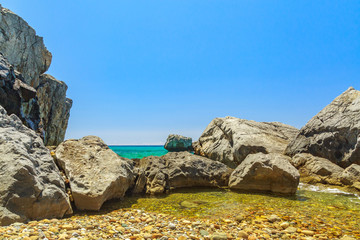 The rocky coast  overlooking the turquoise blue sea in warm summer day.