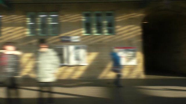 Blurred moving train passenger window view of English and Scottish border city of Carlisle railway station with people standing at the platform