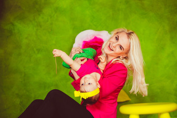 Blonde mother turns upside down her little daughter in pink shirt