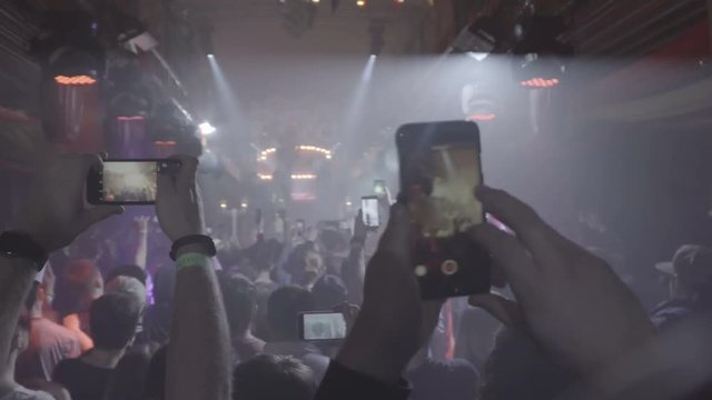 People taking photos or recording video with their smart phones at music concert. Night party, night rave.