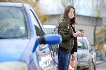 Fototapeta na wymiar Teenager wird durch smartphone und Musik vom Straßenverkehr und von Autos abgelenkt
