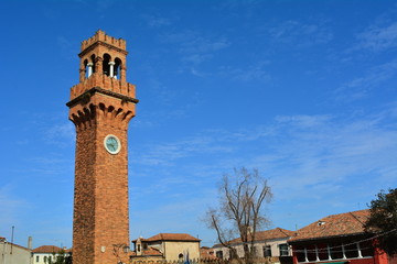 The bell tower with clock on the beautiful island of Murano in Venice, Italy