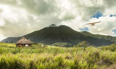 plane flying over huts in remote tropical location © Wollwerth Imagery