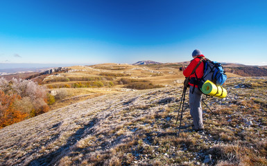 Photographer takes pictures on top of the mountain in autumn. Traveler with backpack enjoying a view from the mountain top