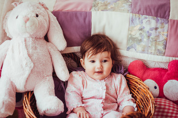 Pretty little girl sits in the basket among large pink toys