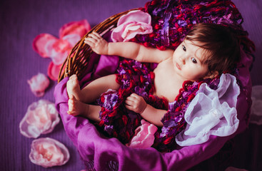 Naklejka premium Funny girl looks up lying in basket full of cloth flowers