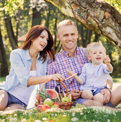 Happy family having a picnic in the park and eating pretzel sticks.