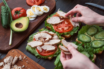 girl chef making sandwich in rustic style with turkey meat and chicken and vegetables