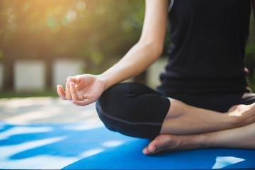 Woman practicing meditation yoga at home with sunset.