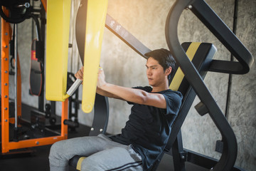 Fototapeta na wymiar Young fitness man execute exercise with exercise-machine in gym. Workout concept.