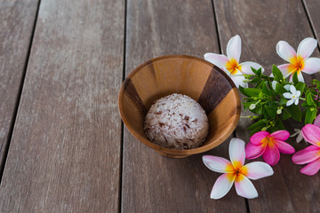 Thailand rice in a sealed timber on a wooden deck with plumeria blossoms beautifully.