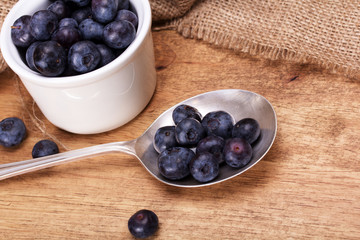 Pot of blueberries with spoon on a rustic background