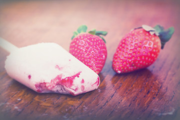 Homemade strawberry ice lolly on rustic background
