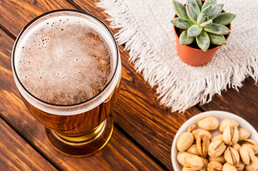 glass of dark cold frothy beer, nuts old wooden table