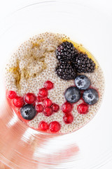Eating healthy breakfast bowl. chia seeds pudding, cranberry, seeds, fresh blueberry and blackberries with  Maple syrup in  bowl on morning table. Clean eating, dieting, detox, vegetarian food concept