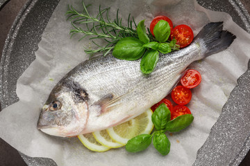 Raw fish cooking and ingredients. Dorado, lemon, herbs and spices. Top view on stone table