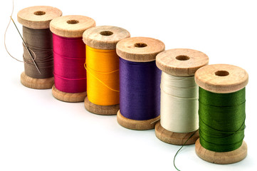Isolated wooden spools of thread with a needle
