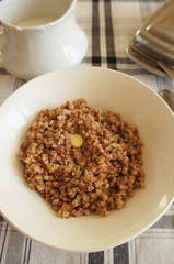 Breakfast on checked table-cloth boiled buckwheat with butter vertical.