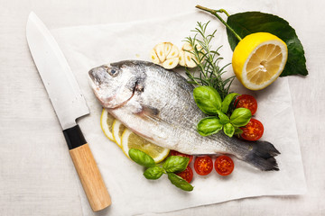 Raw fish cooking and ingredients. Dorado, lemon, herbs and spices. Top view on stone table
