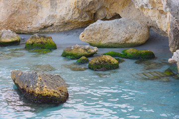 Place bathing beach in the bay at the rocky coast of the sea.