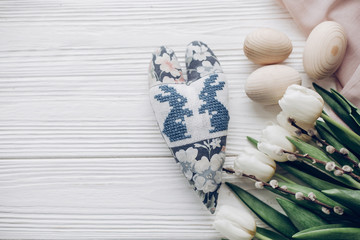 stylish white tulips easter eggs and bunny floral heart on rustic wooden background top view. happy easter greeting card concept with space for text flat lay. soft light