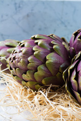 Obraz premium Fresh big Romanesco artichokes green-purple flower heads ready to cook