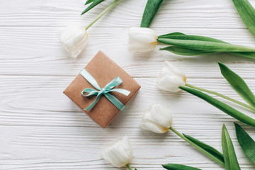 stylish craft present box and tulips on white wooden rustic background. flat lay with flowers  with space for text. hello spring. happy day concept. instagram photo workshop