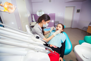 pretty little girl opening his mouth wide during treating her teeth by the dentist