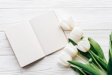 craft notebook, pen and stylish tulips on white wooden rustic background. flat lay with flowers and paper note with space for text. woman working. idea book. fresh start  happy mothers womens day