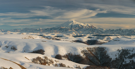 Russia, the Caucasian mountains. Lenticular clouds over the top of of the Elbrus volcano in the winter at sunset.