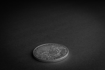 Silver one dollar coin laying on black surface - business concept, isolated.