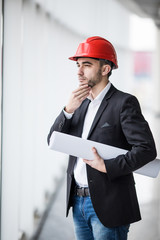 Man in hard hats at building with plans thinking
