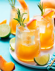 Peach cocktail, fizz, ice tea with fresh rosemary and lime. Blue background.