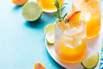 Peach cocktail, fizz, ice tea with fresh rosemary and lime. Blue background. Copy space.