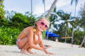 cute little girl in sunglasses and a swimsuit on the beach in paradise by the sea. Travel and Vacation. Freedom