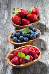 assortment of fresh seasonal berries in a wooden bowl, vertical
