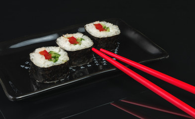 Sushi roll with chopsticks on black background
