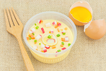 Thai steamed egg with fresh beaten egg and fork decoration on sack background