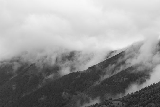 Natural scenery with misty weather. Mist, fog and haze over peaks and summits of mountains. Mysterious atmosphere of black and white landscape © M-SUR